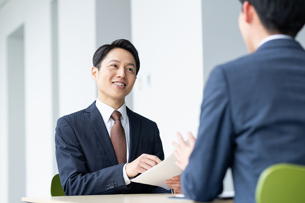 ビジネスマン同士が打ち合わせをしている様子。原稿作成の相談シーンのイメージ